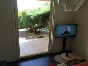 コゴランにあるStudio climatisé piscine parking - Prix du Voyageur 2023 et 2024 ! Merciのリビングルーム(テレビ付)、ガラスのスライドドア