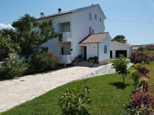 uma grande casa branca com um quintal com flores em Apartments Smilja em Ljubac