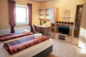 a room with two beds and a desk and a television at Lebererhof Apartments in Roßtal