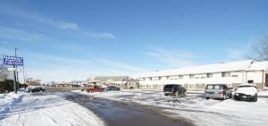 una calle cubierta de nieve con coches aparcados frente a un edificio en Faribault Hometown Inn & Suites, en Faribault