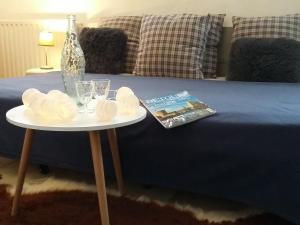 een tafel met een fles en een tijdschrift naast een bed bij gîte les petits poissons verts et massages in La Jarrie