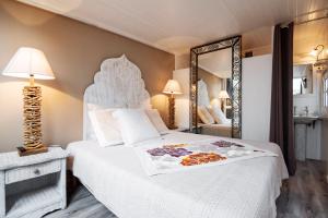 a bedroom with a large white bed and a mirror at Campo Di Fiori, Maisons de Charme in Calvi