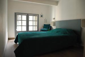 a bedroom with a green bed and a window at CENTRE HISTORIQUE T3 DUPLEX PARKING Gratuit in Béziers