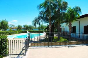 una valla alrededor de una piscina con palmeras en Villa Sammy, en Acquarica del Capo