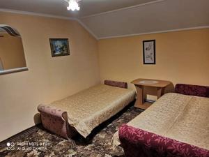a hotel room with two beds and a table at Садиба "Барвінок" in Podobovets