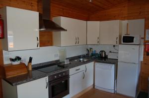 a kitchen with white cabinets and white appliances at Woodland Pine Lodge in Killin