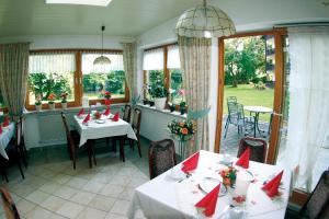 ein Restaurant mit Tischen und Stühlen mit roten Bögen in der Unterkunft Hotel Garni Hubertushof in Bad Füssing