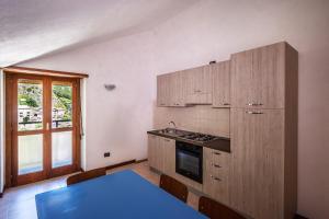 a kitchen with wooden cabinets and a blue table at Hostel - Bormio - Livigno - Santa Caterina - Stelvio in Sondalo
