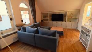 uma sala de estar com um sofá azul e uma televisão em Haus Wopke em Borkum