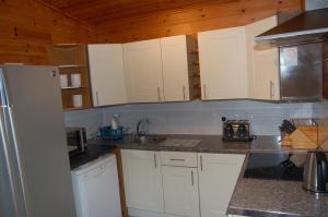 cocina con armarios blancos y nevera blanca en Woodland Gean Lodge, en Killin