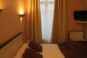 um quarto com uma cama, uma televisão e uma janela em Hotel Napoléon em Cherbourg en Cotentin