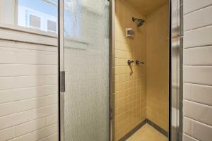 a glass shower door in a bathroom with yellow tiles at Downtown Austin Apt with Patio, Perfect for Two! in Austin