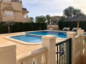 - une piscine avec un parasol en face d'une maison dans l'établissement Beach Front Ground Floor Flat Playa San Juan, à El Campello