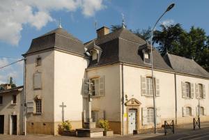 un vieux bâtiment blanc avec une croix dans une rue dans l'établissement La Maison des Gardes - Chambres d'hôtes, à Cluny
