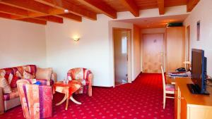 a living room with chairs and a table and a television at Landhotel Basler Hof in Lauterbach