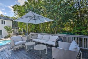 a patio with couches and a table and an umbrella at Modern Miami Villa with Pool Oasis about 5 Mi to Beach! in Biscayne Park
