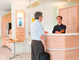 two men standing at a counter in a pharmacy at ibis budget Krefeld Messe-Düsseldorf in Krefeld