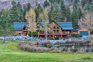 a log house with a pond in front of it at Custom Bitterroot Valley Cabin with Hot Tub and Views! in Conner