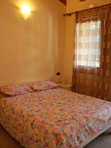 a bedroom with a bed with a floral bedspread and a window at Agriturismo Ca Noale in Teolo