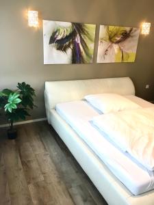 un letto bianco in una stanza con due dipinti sul muro di Four a Coblenza