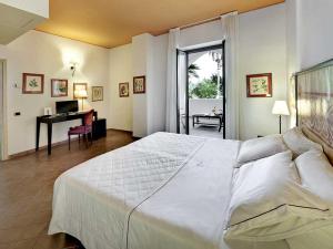 a bedroom with a large white bed and a desk at Hotel Garden in Vulcano
