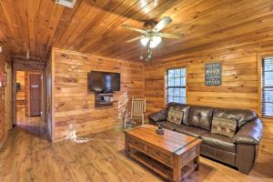 a living room with a leather couch and a tv at Starstruck Cabin with Spa 4 Mi to Broken Bow Lake! in Stephens Gap