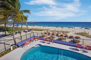 - une piscine à côté d'une plage avec des chaises et l'océan dans l'établissement Ocean Treasure Beachside Suites, à Fort Lauderdale