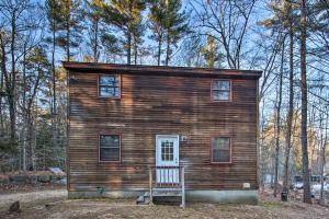 una pequeña cabaña de madera en el bosque con un banco en Lakeview Forest Cabin with Deck Less Than half Mile to Beach!, en Madison