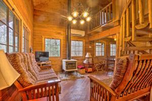 a living room with chairs and a television in a cabin at Scenic Log Cabin with Fire Pit and Stocked Creek! in Titusville