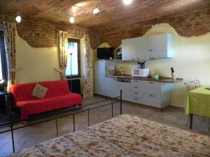 a living room with a red couch and a kitchen at Agriturismo Fano's Farm in Suno