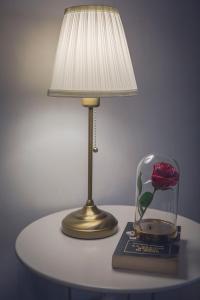 a table with a lamp and a flower in a glass jar at Da Alessia Per Dormire Al Coppedé in Rome