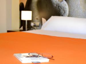 a pair of glasses sitting on a book on a bed at Hostal Bajo La Muralla in Zamora