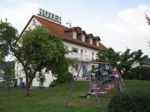 un parque infantil frente a un hotel con un edificio en Hotel Linden, en Knüllwald