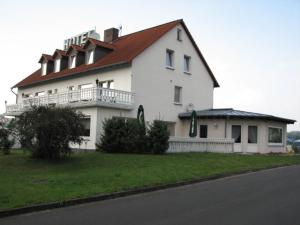 ein großes weißes Haus mit rotem Dach in der Unterkunft Hotel Linden in Knüllwald