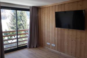 a living room with a television on a wooden wall at Résidence Luxe 5*,Spa & Fitness, La Cordée Appartement 821 in Chamonix-Mont-Blanc