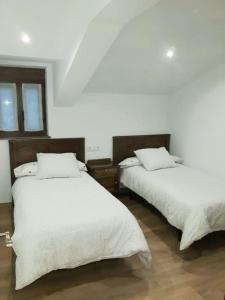 Habitación con 2 camas, paredes blancas y suelo de madera. en EL MEJICANO, en Trevías