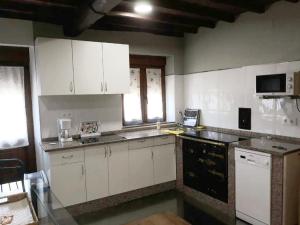 a kitchen with white cabinets and a glass table at EL MEJICANO in Trevías