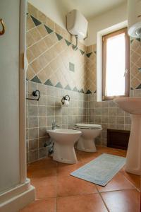 bagno con due servizi igienici, lavandino e finestra di Agriturismo Carrucana a Martis