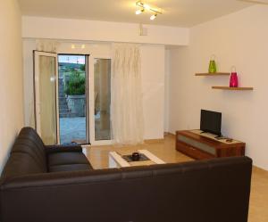 a living room with a couch and a television at Villa Dimitri - GardenSide Souterrain in Alexandroupoli