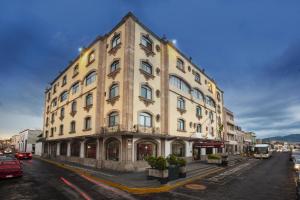 a large building on a city street with cars at Vista Express Morelia by Arriva Hospitality Group in Morelia