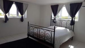 une chambre avec un lit noir et deux fenêtres dans l'établissement Villa Mila, 4 Bedroom holiday home with private pool and tropical view in a quiet residential area of Willemstad, Curacao, à Willemstad 39 autres photos