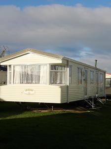 a mobile home is parked in a yard at Lovely 4 berth static caravan, Marine Holiday Park, Rhyl, Wales in Rhyl