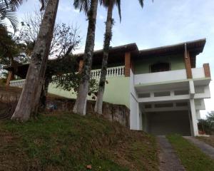 une maison avec des palmiers devant elle dans l'établissement Chacara Recanto do Carlão, à Biritiba-Mirim