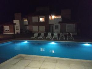 a swimming pool at night with chairs and a building at Mirador Suites & Aptos in Villa General Belgrano +2 photos