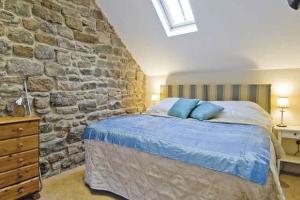 Un dormitorio con una pared de piedra y una cama en Riding Farm Cottages en Gateshead