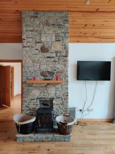 una chimenea de piedra en una sala de estar con 2 cestas en 19 Drumcoura Lake Resort, en Ballinamore