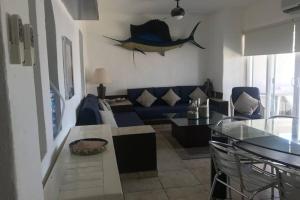 a living room with a blue couch and a fish on the wall at CÓMODO DEPARTAMENTO 360 Puerto Las Hadas in Manzanillo