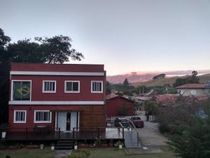 uma casa vermelha com uma bandeira ao lado dela em Quarto Aconchegante em São Bento do Sapucaí
