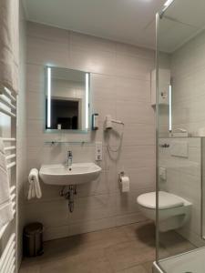 a bathroom with a sink and a toilet and a mirror at Restaurant - Pension Im Pfenn in Irrhausen