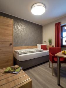 a bedroom with a bed and a red chair at Restaurant - Pension Im Pfenn in Irrhausen